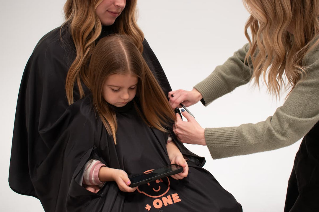 Child watching tablet during haircut using +ONE haircutting cape